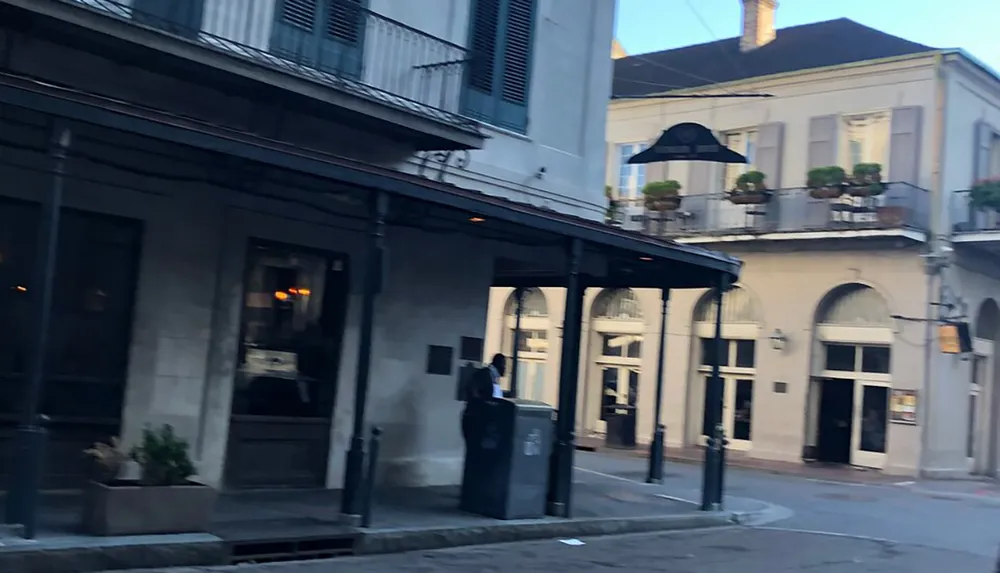 The image shows a street corner with historic architecture including balconies and a lamppost indicative of a charming urban district possibly in a city like New Orleans