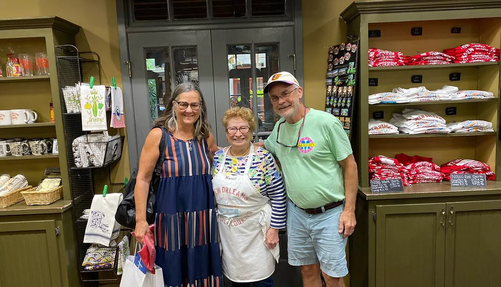 Three smiling adults are posing for a photo inside a shop with shelves displaying souvenirs and culinary products