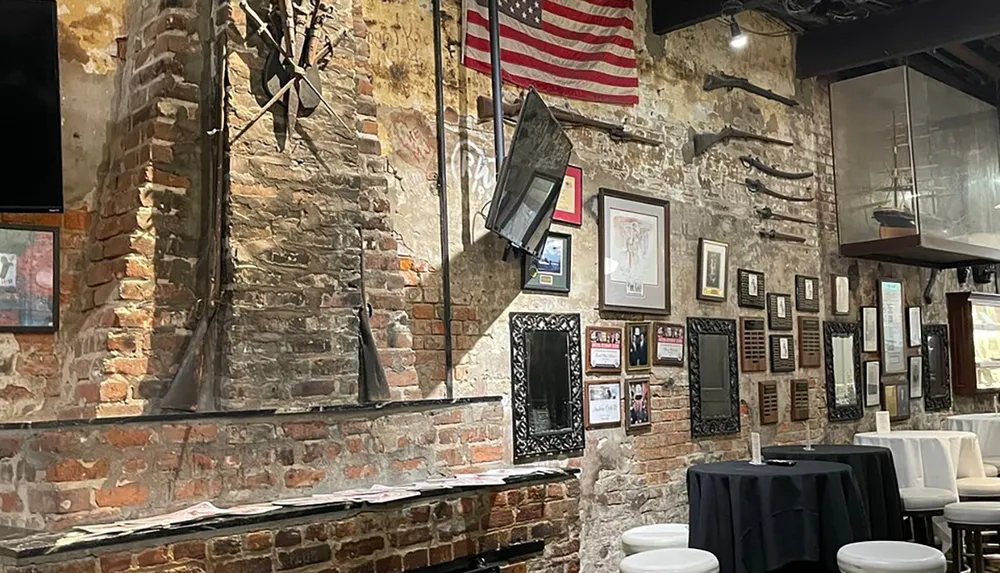 The image shows an interior space with exposed brick walls decorated with framed pictures old rifles an American flag various mounted artifacts and a model ship suggesting a thematic or historical motif in a dining or public gathering area