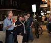 A group of people is attentively listening to a guide during an evening walking tour on a city street