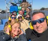 A group of smiling people wearing protective ear muffs are enjoying a ride on an airboat with waterfront homes visible in the background