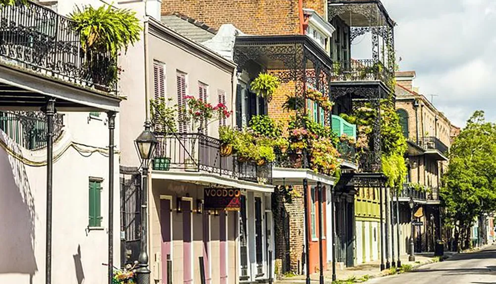 The image shows a vibrant street lined with colorful historical buildings featuring ironwork balconies and hanging plants reminiscent of the French Quarter in New Orleans