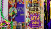 The image displays a vibrant Mardi Gras-themed vodka bottle labeled 