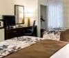 The image shows a neatly arranged hotel room with a living area and an adjacent sleeping area decorated in a modern style with earthy tones