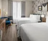 The image shows a neatly arranged hotel room with two beds elegant decor and a workspace