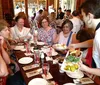 A group of people is enjoying a meal at a restaurant while a server brings more food to the table