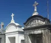 The image shows an ornate entrance gate to Saint Roch Campo Santo cemetery with statues on either side and a sunlit path leading into the burial grounds