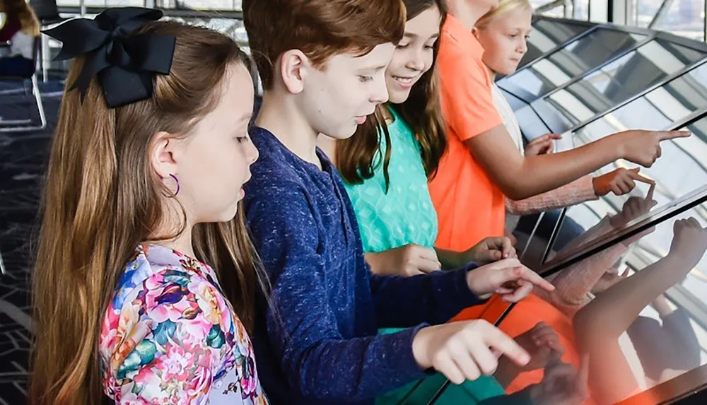 A group of children is engaging with an interactive digital display