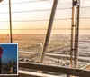 The image shows a view from a tower overlooking a cityscape at sunset with a telescope in the foreground and an inset image of a tower illuminated at night