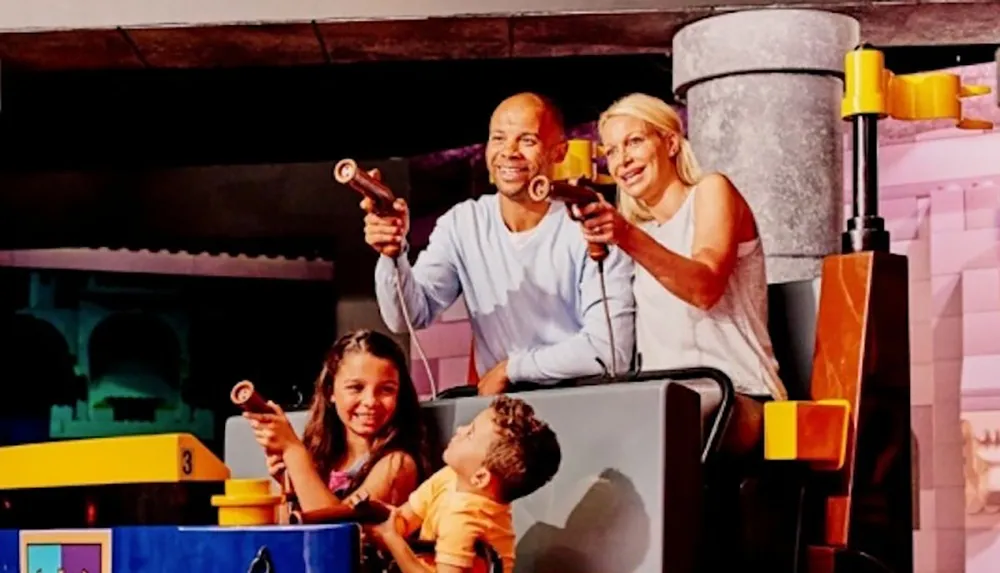 A family is joyfully engaging in an interactive dark ride with each member holding a blaster aiming at targets within the attraction