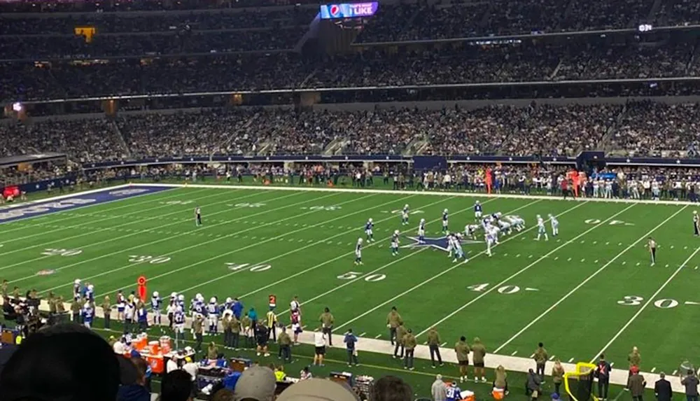 This image captures a moment during an American football game in a large stadium filled with spectators