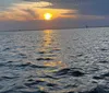 Three friends are enjoying a boat ride with a beautiful sunset over the water in the background