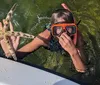 A person wearing a snorkeling mask emerges from the water holding a large starfish near the side of a boat