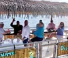 A group of people is enjoying a boat ride on a sunny day with a straw-covered overhang waving and smiling at the camera