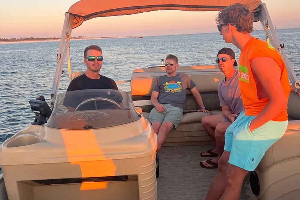 Three people are enjoying a boat ride during sunset two seated and one standing with the water and horizon in the background