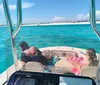 Two adults and a child are relaxing on a boat with clear turquoise waters in the background