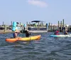 Several people are kayaking near a dock with boats on a sunny day