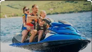 Three people, an adult and two children, are having fun riding a blue jet ski on a sunny day.