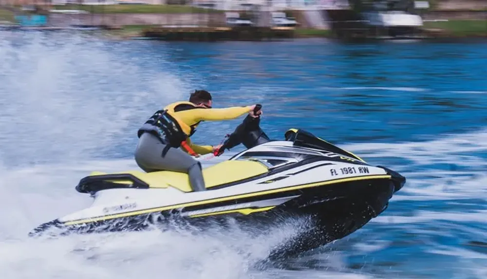 A person is riding a yellow and black jet ski on the water at high speed