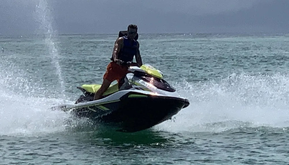 Two people are riding a jet ski on a body of water creating a splash