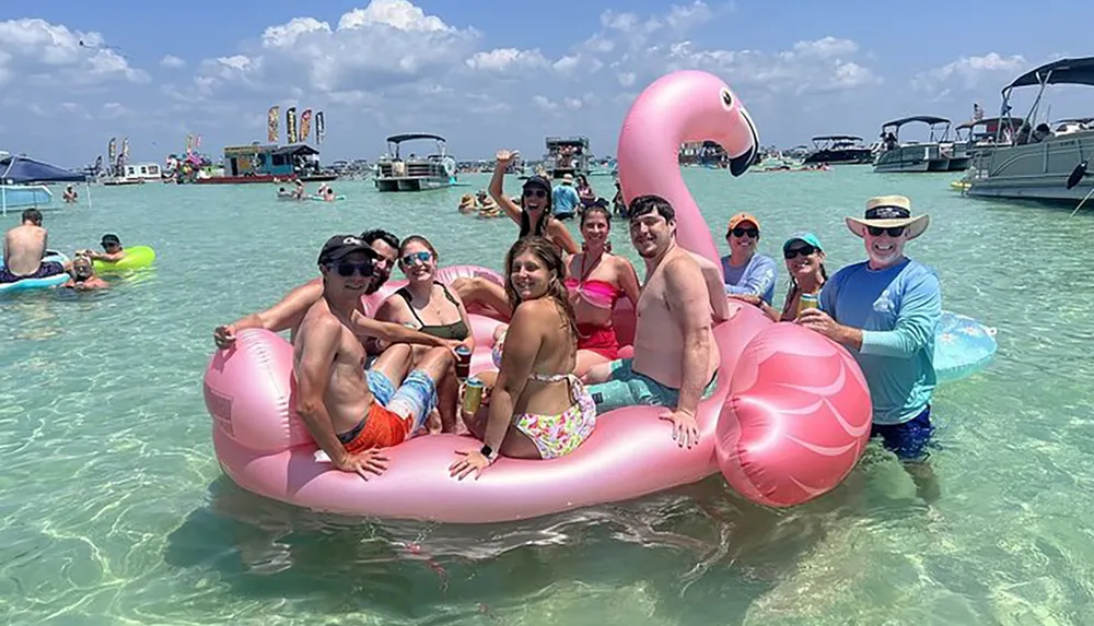 A group of people are enjoying a sunny day in the water with a giant pink flamingo float surrounded by other beachgoers and boats