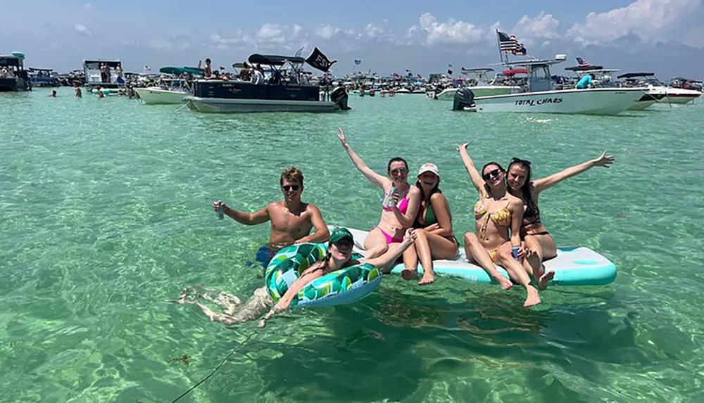 A group of people is enjoying a sunny day in clear water with inflatable floats surrounded by boats expressing joy and relaxation