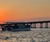 A group of five people are smiling and posing together on a boat with a beautiful sunset in the background