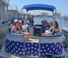 A group of smiling people is enjoying a sunny day on a boat with patriotic American flag-themed covers on the seats