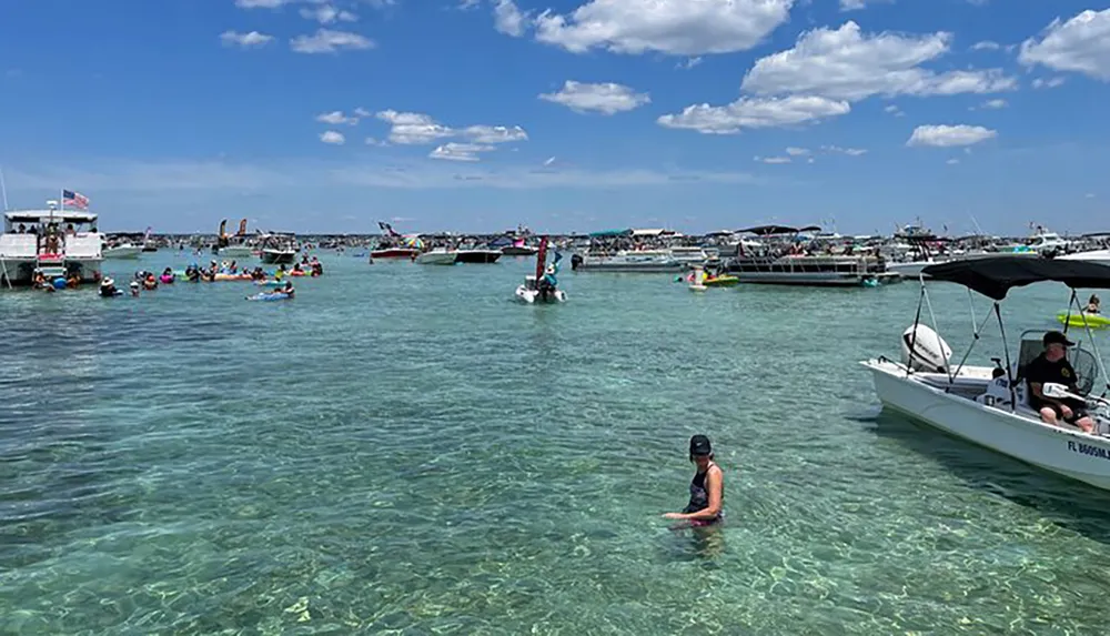 The image depicts a bustling aquatic gathering with numerous boats and people enjoying the clear waters on a sunny day