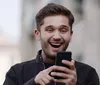 A group of cheerful young adults is taking a selfie with one of them holding the camera out in front capturing their smiling faces