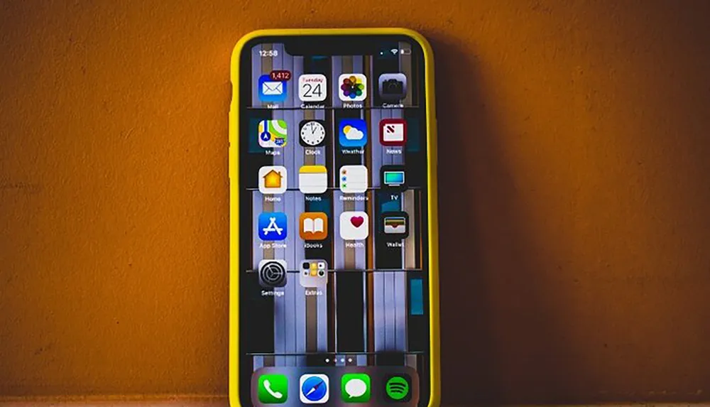 The image shows a smartphone with a yellow case displaying a grid of various app icons against an orange background