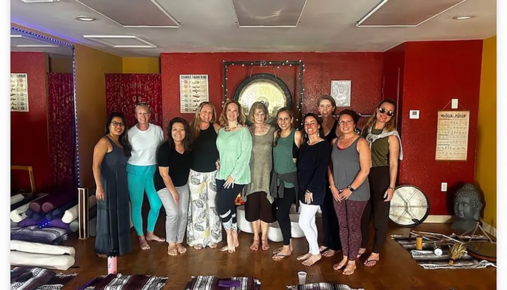 A group of smiling individuals is posing together in a room with yoga mats and meditation decor