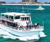 A double-deck tour boat named Southern Star filled with passengers is cruising in vibrant blue waters close to the shore with buildings in the background and another smaller boat speeding by in the distance