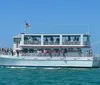 A double-deck tour boat named Southern Star filled with passengers is cruising in vibrant blue waters close to the shore with buildings in the background and another smaller boat speeding by in the distance