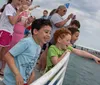 A double-deck tour boat named Southern Star filled with passengers is cruising in vibrant blue waters close to the shore with buildings in the background and another smaller boat speeding by in the distance