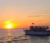 A tour boat is filled with passengers as they enjoy a vivid sunset over the water