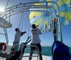 Two people on a boat are managing a parasail against a backdrop of blue sky and sea