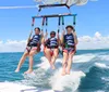 Two people on a boat are managing a parasail against a backdrop of blue sky and sea