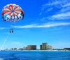 Two people on a boat are managing a parasail against a backdrop of blue sky and sea