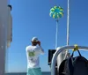 Two people on a boat are managing a parasail against a backdrop of blue sky and sea