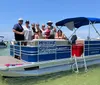 A group of people enjoys a sunny day on a pontoon boat on calm waters with other boats in the background