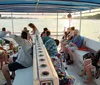 A group of people are enjoying a boat tour during sunset with some sitting on benches and others standing surrounded by calm waters