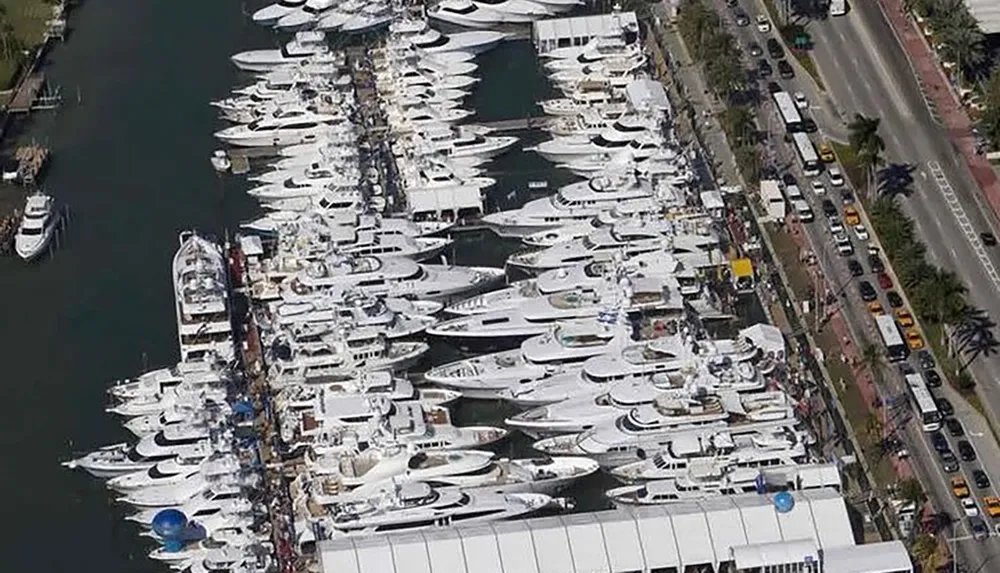 Aerial view of a densely packed marina filled with numerous yachts adjacent to a busy street with traffic