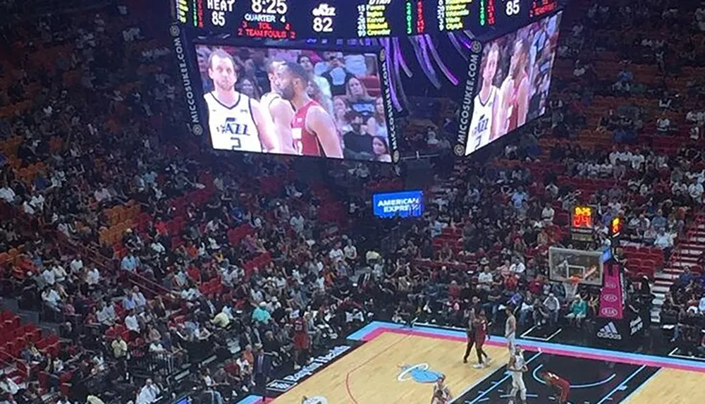 A basketball game is in progress with fans in the stands and the scoreboard shows the Miami Heat leading the Utah Jazz in the fourth quarter with a score of 85 to 82 and 825 remaining on the clock