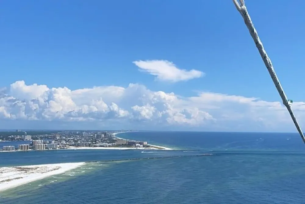 The image shows a coastal cityscape viewed from above featuring turquoise waters a clear blue sky and a rope entering the frame from the top right corner suggesting the photo was taken either from a tall structure or an elevated position like a hill or a high-rise