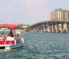 A group of people enjoy a boat ride near a bridge with a large building complex in the background