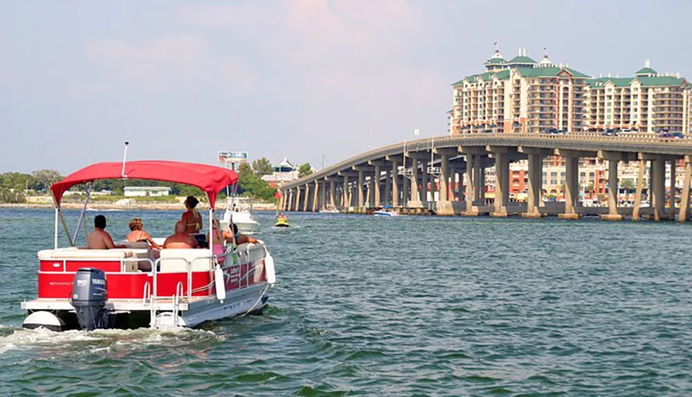 A group of people enjoy a boat ride near a bridge with a large building complex in the background