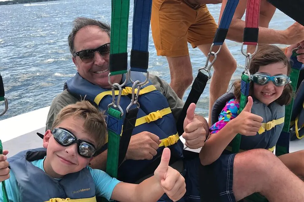 A group of people including two enthusiastic children giving thumbs up are all smiles as they prepare for a parasailing adventure at sea