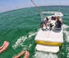 Three individuals are enjoying parasailing above the ocean with smiles on their faces suggesting they are having a great time