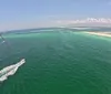 Three individuals are enjoying parasailing above the ocean with smiles on their faces suggesting they are having a great time